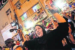 A libyan woman raises a rifle as thousands of her compatriots celebrate what the rebels claim to be the first uprising in Tripoli against Muammar Gaddafi at freedom square in Benghazi on Sunday