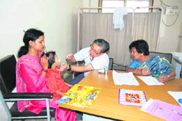 Dr Fong Poh Him, Chairman, Institute of Plastic Surgery, Singapore, examines a child at a camp at the Tanda medical college on Monday