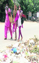 Girls cover their noses as they pass by a garbage dump in Nawanshahr.