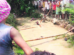 Villagers carry out rescue work after a tractor-trailer carrying over 60 devotees overturned and fell into a ditch near Nagla in Ballia on Monday