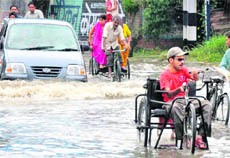 A physically challenged person crosses the flooded Bhagat Singh Chowk area in Haridwar 