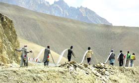 Workers carry high-tension wires to be installed in a remote area in Kargil
