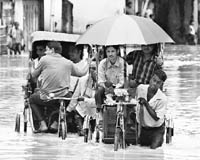 Cycle-rickshaw pullers ferry commuters through floodwaters in Dimapur. 