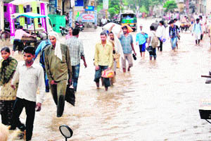 People wade through a flooded street in Palwal. 