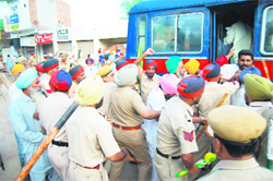 Cops bundle protesting farmers into a van.