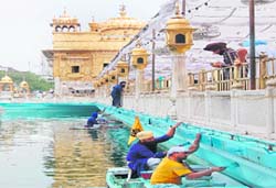 Sewadars paint the sarovar walls at the Golden Temple in Amritsar