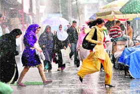 People run for cover as it rains in Srinagar on Saturday.