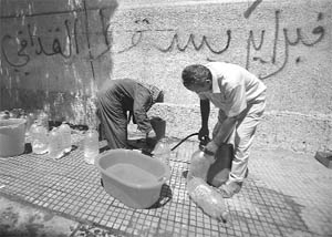 Libyan men fill plastic cans with water from a public tap in Tripoli 