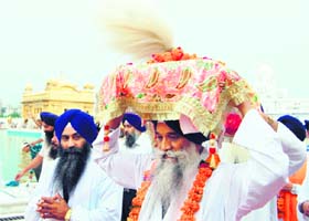 Giani Gurbachan Singh, Jathedar of Akal Takht, carries Guru Granth Sahib during a religious procession at the Golden Temple on the occasion of the 305th Sampoorta Divas in Amritsar on Sunday