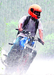 A motorcyclist caught in a sudden spell of rain at Sector 23 in Chandigarh on Friday.