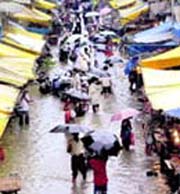 People with umbrellas wade through a street filled with rain water in Mumbai on Sunday.