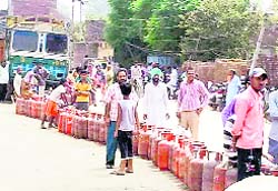 Customers wait for their turn in a queue to get their cylinders filled in Doraha.