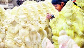 A woman gives final touches to an idol of Lord Ganesha ahead of Ganesh Chaturthi in Ludhiana on Monday.