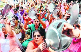 Members of the Anganwari Mulazam Union, Punjab, beat utensils during a demonstration in Chandigarh on Monday. They are demanding salaries on a par with Haryana employees, fixed TA, DA and pension.