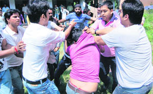 A student is beaten at DAV (PG) College; and (below) police personnel on patrol during the elections in Dehradun on Tuesday. 