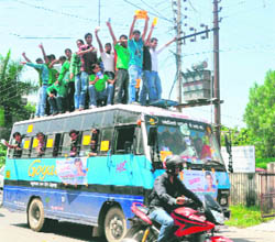Unmindful of the high-tension wires above them, students stand on the roof of a bus going to DAV (PG) College. 
