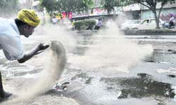 A man throws sand on the road to absorb the oil.