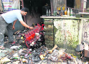 A shopkeeper assesses the damage due to a fire that broke out at his shop near Coronation Hospital in Dehradun 
