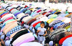 A child watches as Muslim devotees offer Eid-ul-Fitr prayer at a mosque in Karnal 