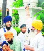 A father protects his son as a Nihang Singh fires in the air outside the SGPC office in the Golden Temple complex during a nagar kirtan in Amritsar 