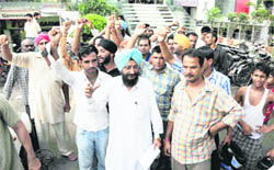 Youths, who were duped by a travel agent, protest outside his office on the Mall road in Ludhiana. 