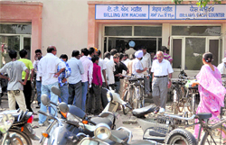 People wait for their turn to make payment of electricity bills through ATM or sewak machines at a PSPCL office in Ludhiana on Friday
