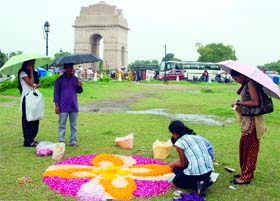 Girls make a "Rangoli' in the rain as part of Onam celebrations at India Gate in New Delhi on Sunday.