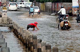 A boy searches for something that he dropped accidentally on a waterlogged road near Hero Honda Chowk in Gurgaon on Sunday.