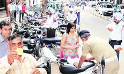 A policeman challans a woman vehicle owner despite her possessing an MC parking slip. Another motorist shows his parking slip opposite the Mehfil restaurant area in Sector 17, Chandigarh, on Monday. 