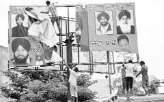 Employees of the municipal council remove hoardings from the Zirakpur-Patiala highway on Monday