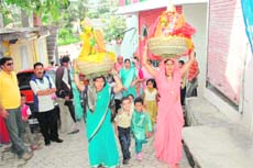Women carry idols of Lord Shiva and Parvati at the Aathon festival 