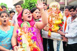 Stand-up comedian Bharti carries an idol of Ganesha for immersion in the Beas in Amritsar