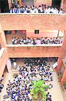 Making a mockery of the specified student-classroom ratio, over 500 students are bundled together in the courtyard and corridors of the Government High School at Mauli Jagran. 