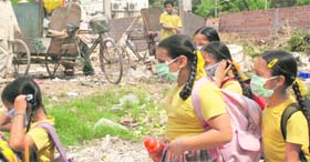 Students too wear masks as they walk past the garbage collection centre located near St Soldier Public School in Phase-VII, Mohali, on Tuesday.