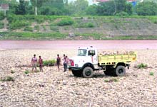 People collect sandstones from the Tawi in Jammu on Wednesday. 