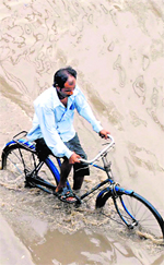 A man cycles his way through a waterlogged road after rain lashed Patiala on Thursday