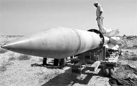 An anti-Gaddafi fighter stands on a SA-5 SAM missile in Burkan air defence military base, which was destroyed by a NATO air strike on September 6, 2011.