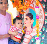 A young child poses with an infant while paying obesiance at Baba Sodal mandir