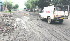 A scene of a muddy and broken road in Transport Nagar.
