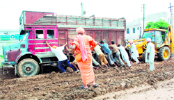 Environmentalist Sant Baba Seechewal looks on as sewadars push a truck stuck in slush in Shahkot