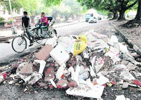 Debris dumped on the road separating Sectors 20 and 21 in Chandigarh poses a serious threat to the lives of motorists