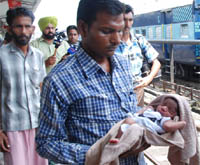 A volunteer of the Sahara Jan Sewa, an NGO, along with a new-born boy that was found lying abandoned in a passenger train, at the Bathinda railway station on Monday. 