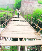 Pedestrians walk over the dilapidated bridge at New Chander Nagar, Haibowal, in Ludhiana