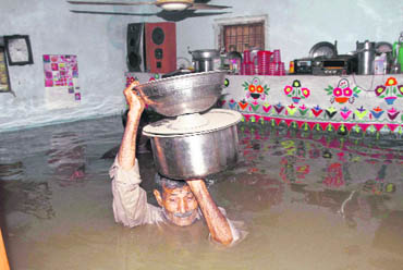 A Pakistani retrieves belongings from a flooded room of his home following heavy rainfall in Karachi
