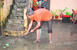 a man tries to drain out rain water from his courtyard.