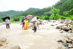A man carries a child who narrowly escaped being swept away in the Noon rivulet 