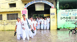 Students of the Government Girls Senior Secondary School, Basti Sheikh, walk out into the inundated street right outside their school in Jalandhar. 