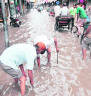 MC employees open a manhole to drain water in Chaura Bazaar in Ludhiana.