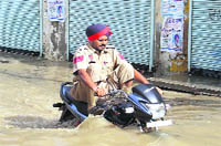 Just A cop wades through a street inundated following rainfall in Mansa