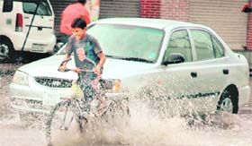 A boy enjoys cycling on a flooded road in Amritsar on Friday.